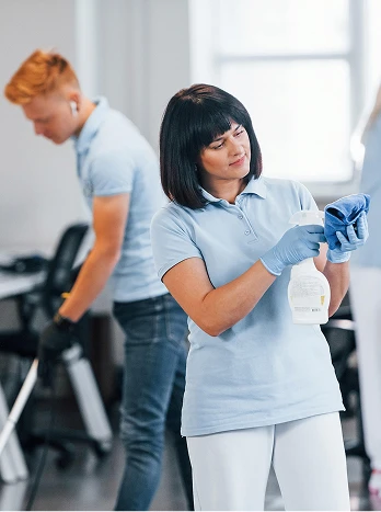 Female physical therapist examining patient's arm while male patient exercises in rehabilitation clinic - Cleaning in the DC Metro area.