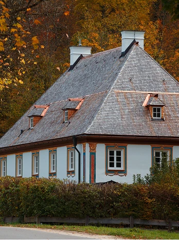 Traditional European cottage with slate roof and white walls surrounded by autumn foliage and hedges - Cleaning in the DC Metro area.