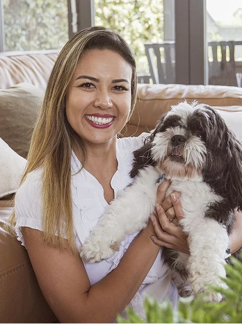 Woman smiling and holding small fluffy black and white dog indoors on couch - Cleaning in the DC Metro area.
