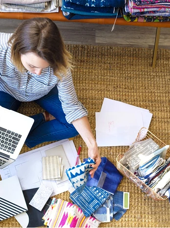 Interior designer working with fabric swatches, color palettes, and laptop at desk from overhead view - Cleaning in the DC Metro area.