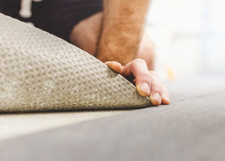 Professional installing beige carpet on floor, showing hand placement and installation technique - Carpet installation in the DC Metro area.