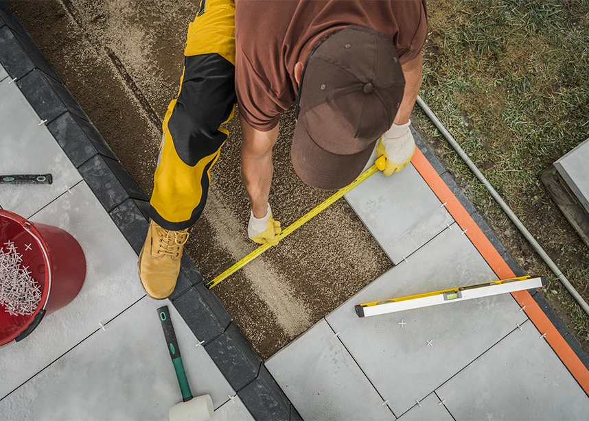 Worker measuring concrete blocks with tape measure and level during construction project from above - Concrete work in the DC Metro area.