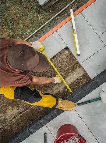 Worker measuring concrete blocks with tape measure and level during construction project from above - Concrete work in the DC Metro area.