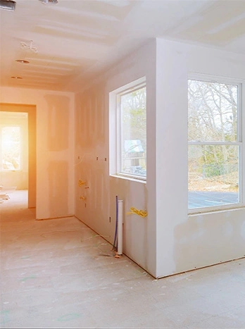 Empty room under construction with drywall walls, white windows, and unfinished flooring in residential home - New construction in the DC Metro area.