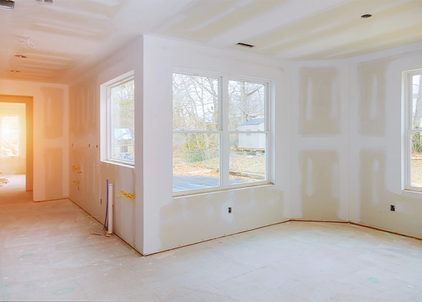 Empty room under construction with drywall walls, white windows, and unfinished flooring in residential home - New construction in the DC Metro area.