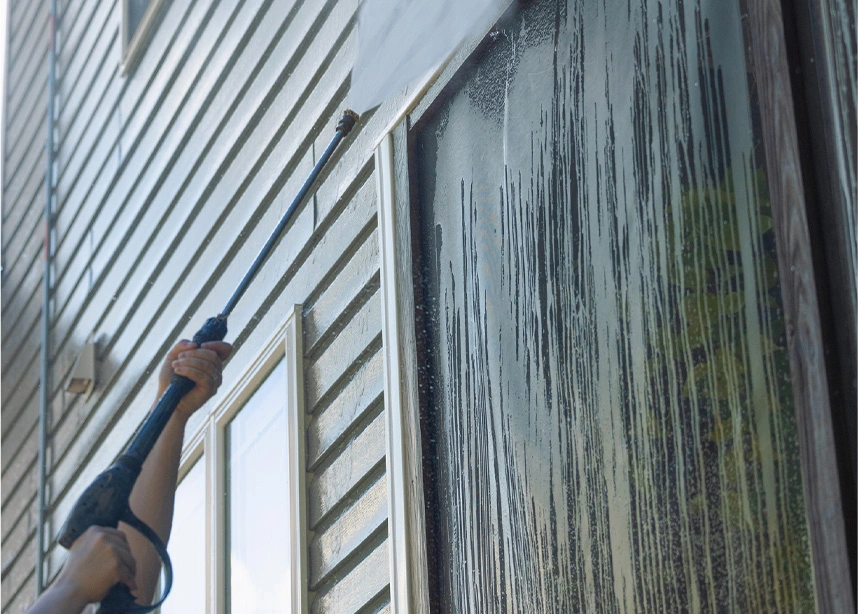 Professional pressure washing cleaning dark mold and grime from vinyl house siding with high-pressure spray - Powerwashing in the DC Metro area.