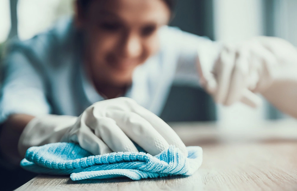 Person cleaning surface with white cloth and blue microfiber towel during building maintenance work - Cleaning in the DC Metro area.